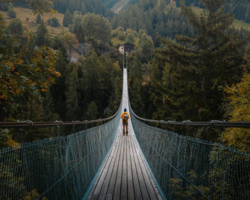 young-traveler-man-dressed-yellow-jacket-crosses-hiking-impressive-wooden-metal-bridge
